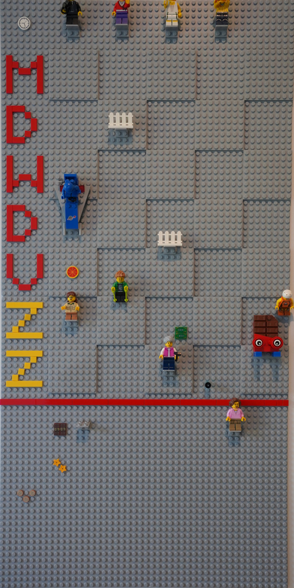 Our LEGO week planner on the wall: grey baseplates, the days in brick letters, a minifigure at the top of each column and small builds on the days.