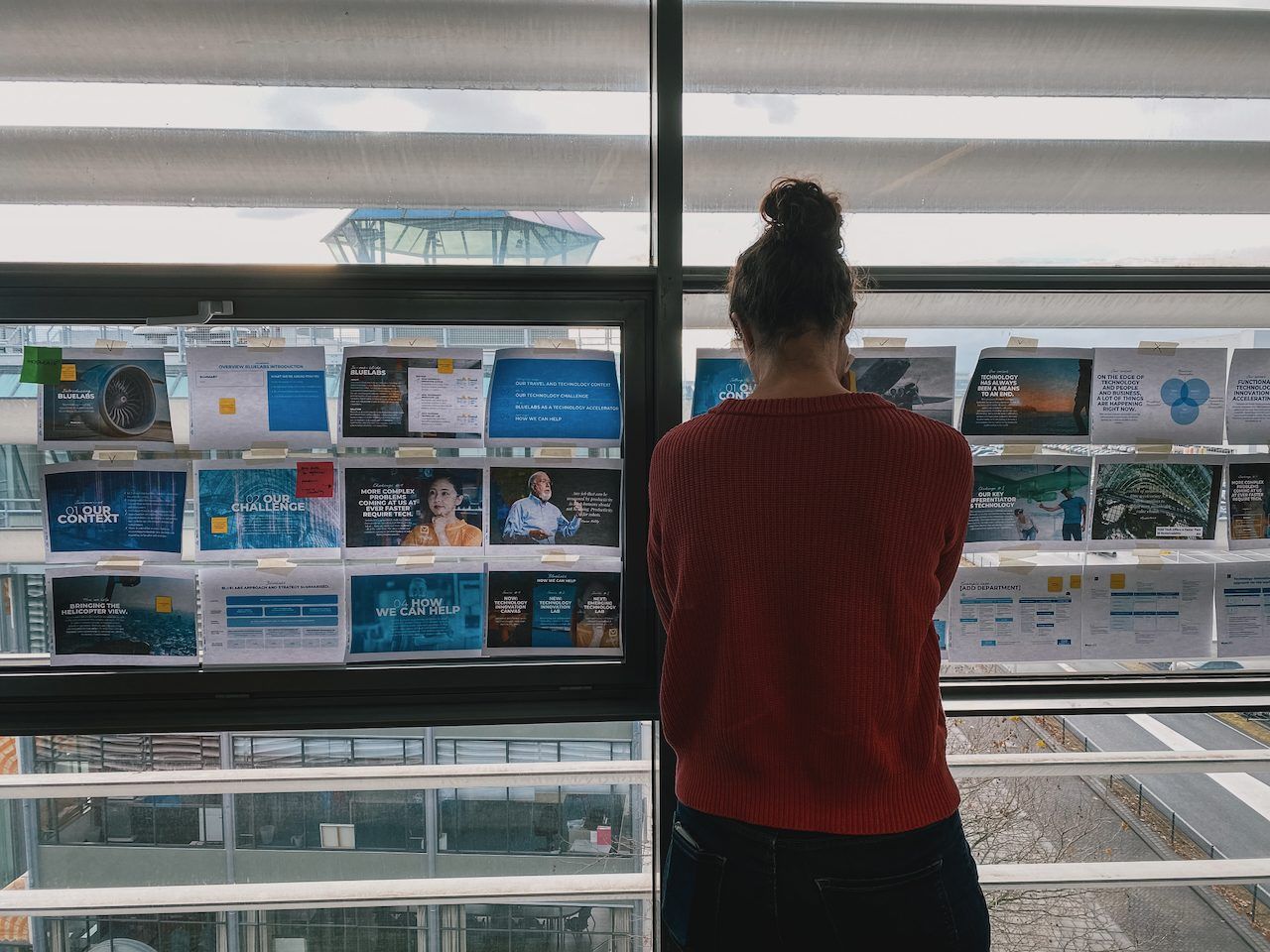 A team member reading a storyline printed and taped to the window, seen from behind