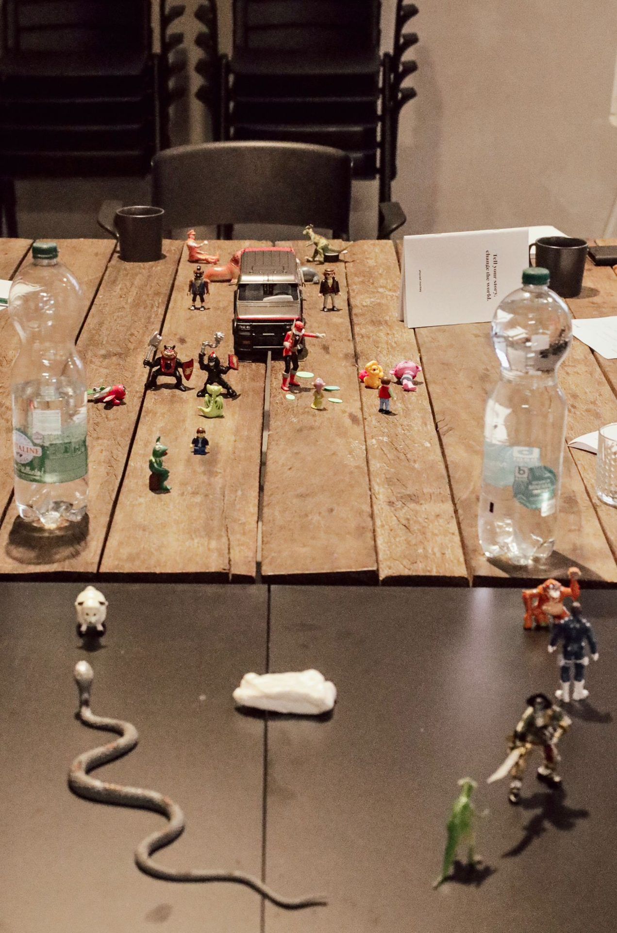 Workshop table seen from above, figurines and a workbook between the water bottles