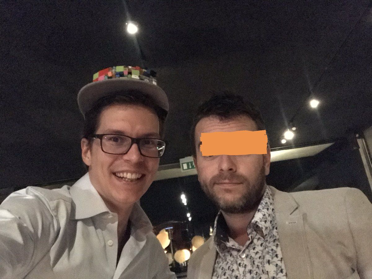 Polle wearing the LEGO cap in a bar in Prague, next to a LEGO colleague whose eyes are covered