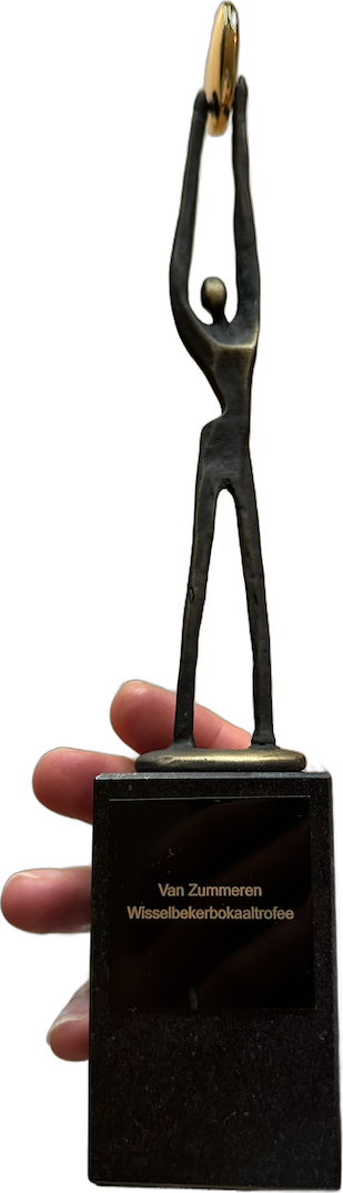 The Van Zummeren trophy: a thin bronze figure holding a golden ring above its head, on a black stone base with a name plate